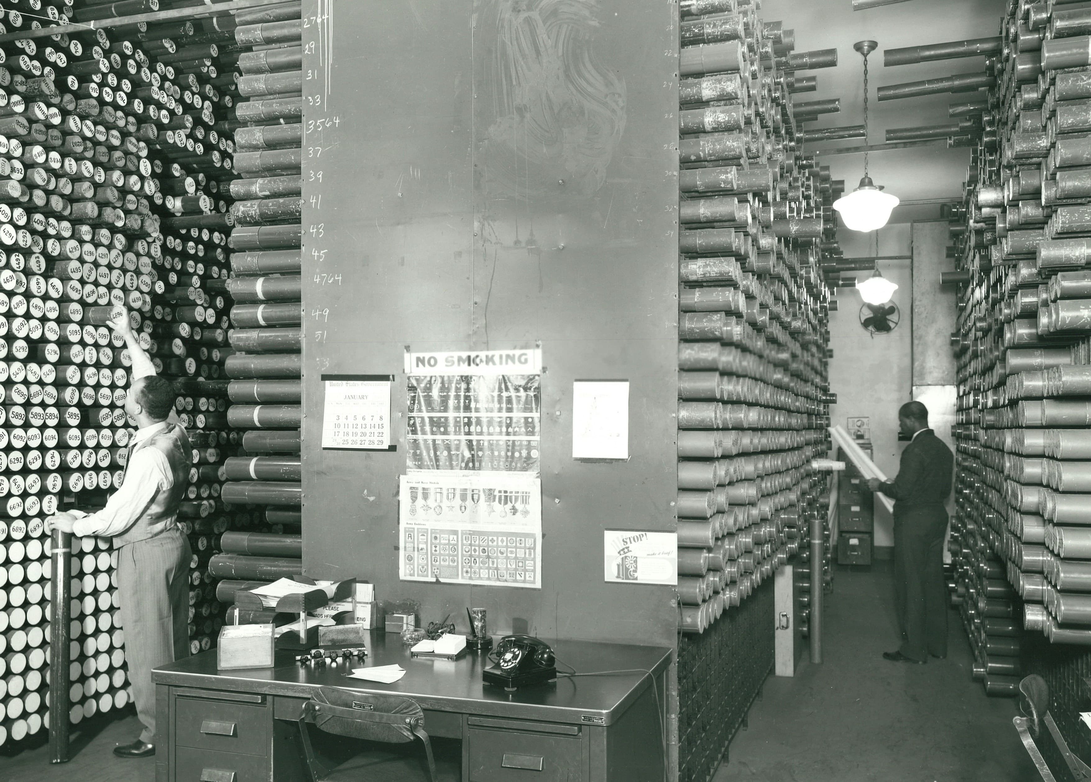 NOAA archive room with workers and shelves of film canisters
